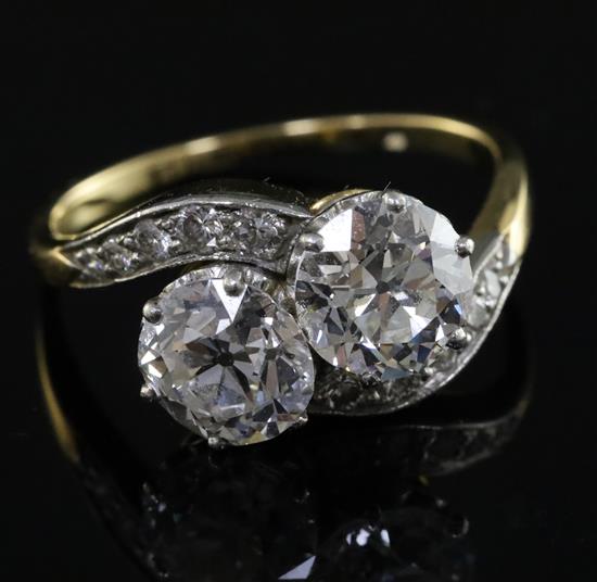 A gold and platinum, two stone diamond crossover ring with diamond set shoulders, size P.